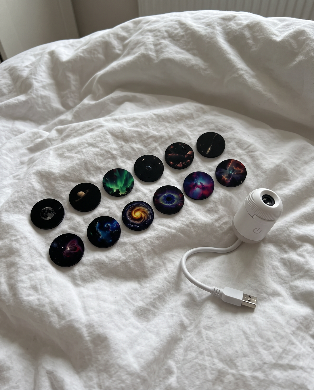 Several round sky projection discs spread out on a white duvet