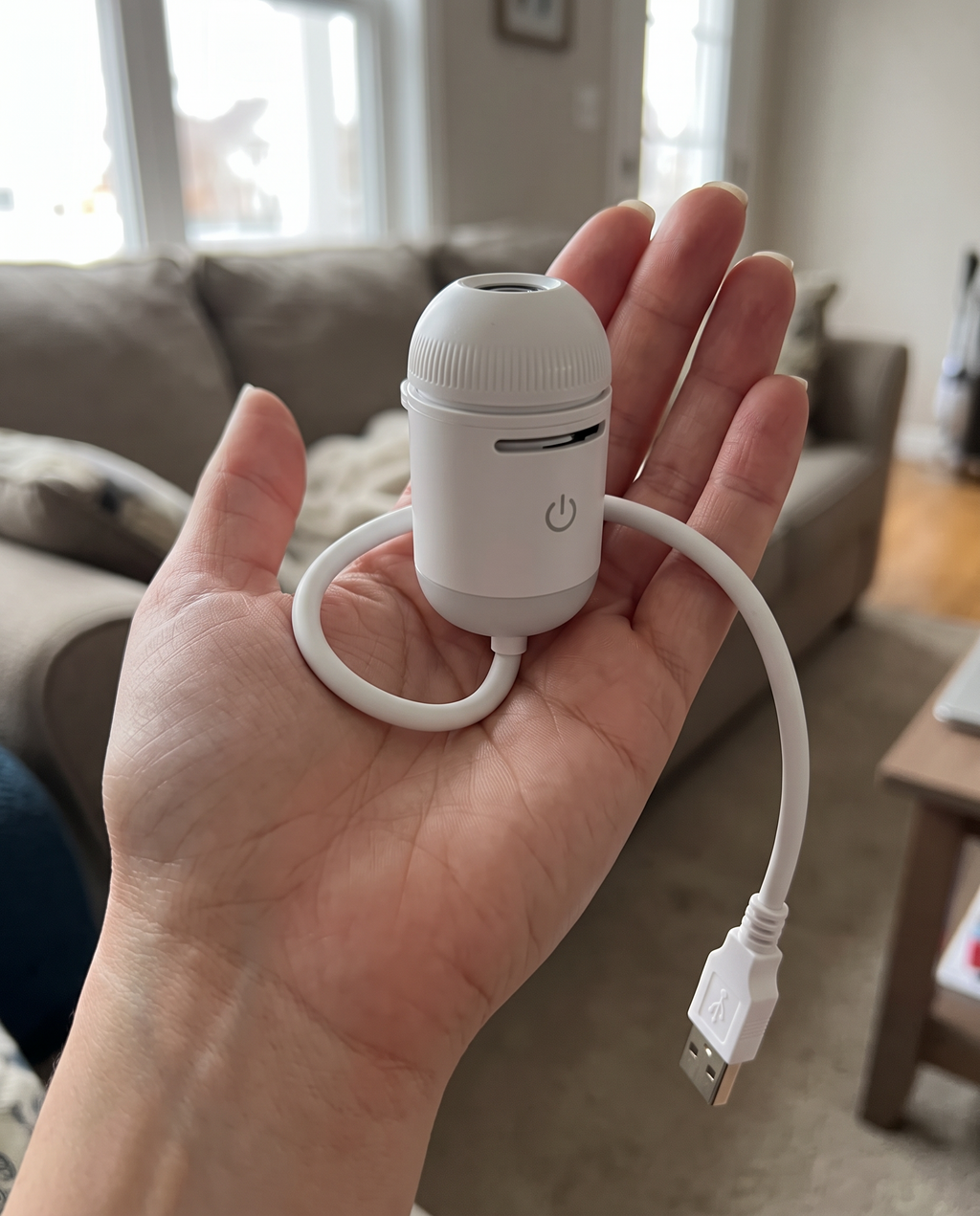 The white mini galaxy projector held in one hand to show its small size