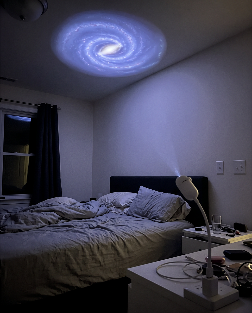 Bedroom ceiling and walls covered in a projected galaxy of stars and nebula clouds at night
