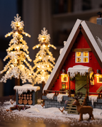 Close-up of the snowy roof, glowing window, log pile and brick reindeer
