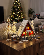 Red A-frame Christmas cabin brick set glowing with warm LED lights in a cozy living room at night